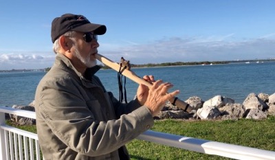 Still from a video of Victor Begg playing his Native American flute along a shoreline