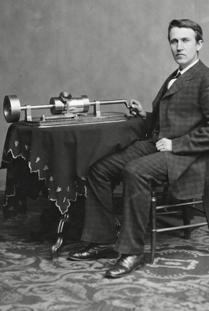 Thomas Edision sits next to his phonograph