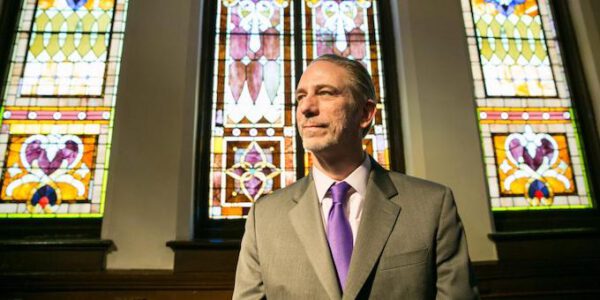 David Gushee in front of stained glass windows