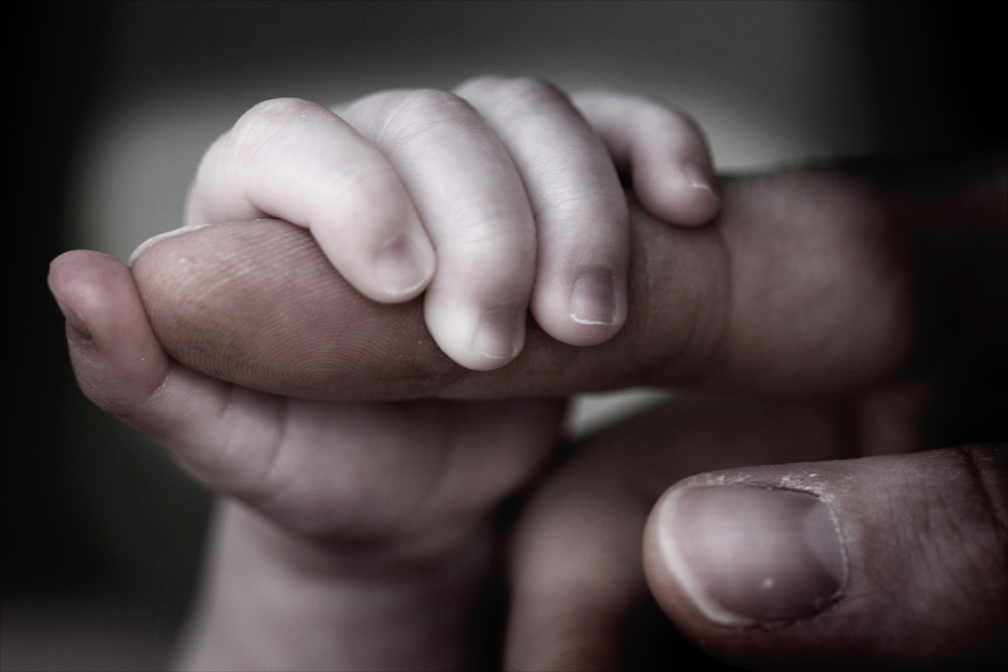 Baby holding parents finger