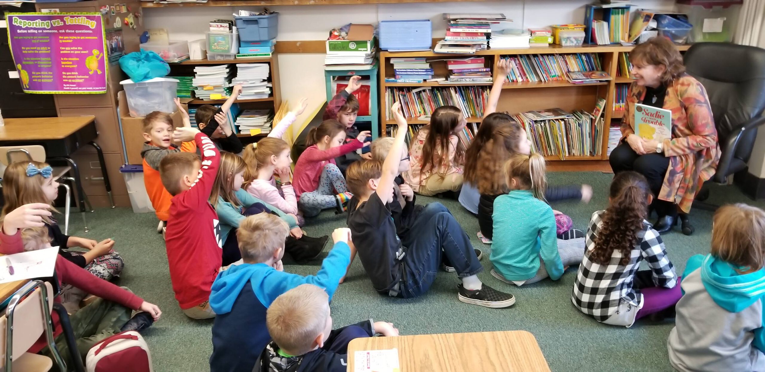 Linda Jarkley in front of a group of elementary school students with hands raised