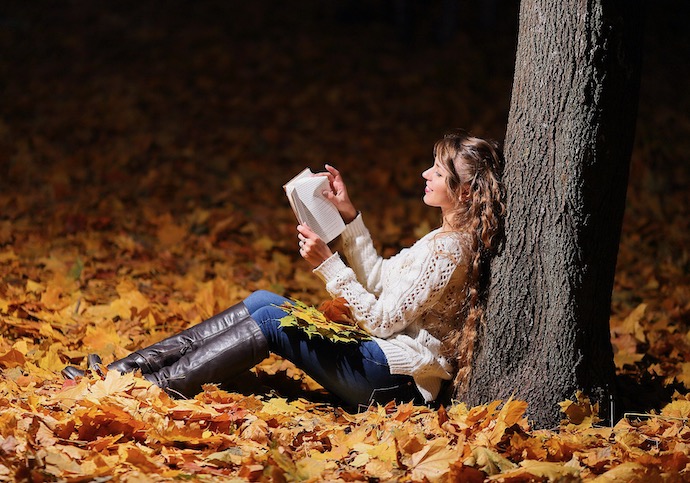 Woman reading under a tree in the woods